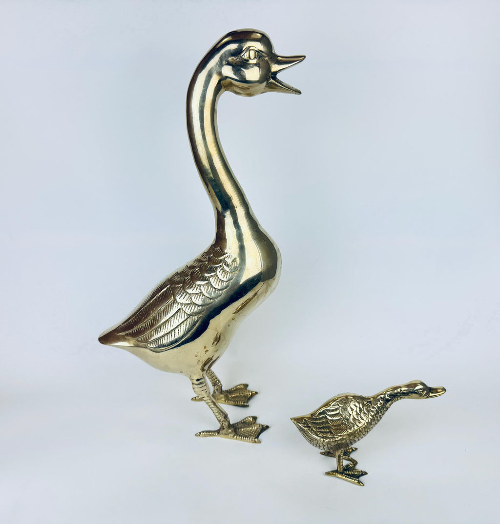 Two gold duck figurines on a light gray background
