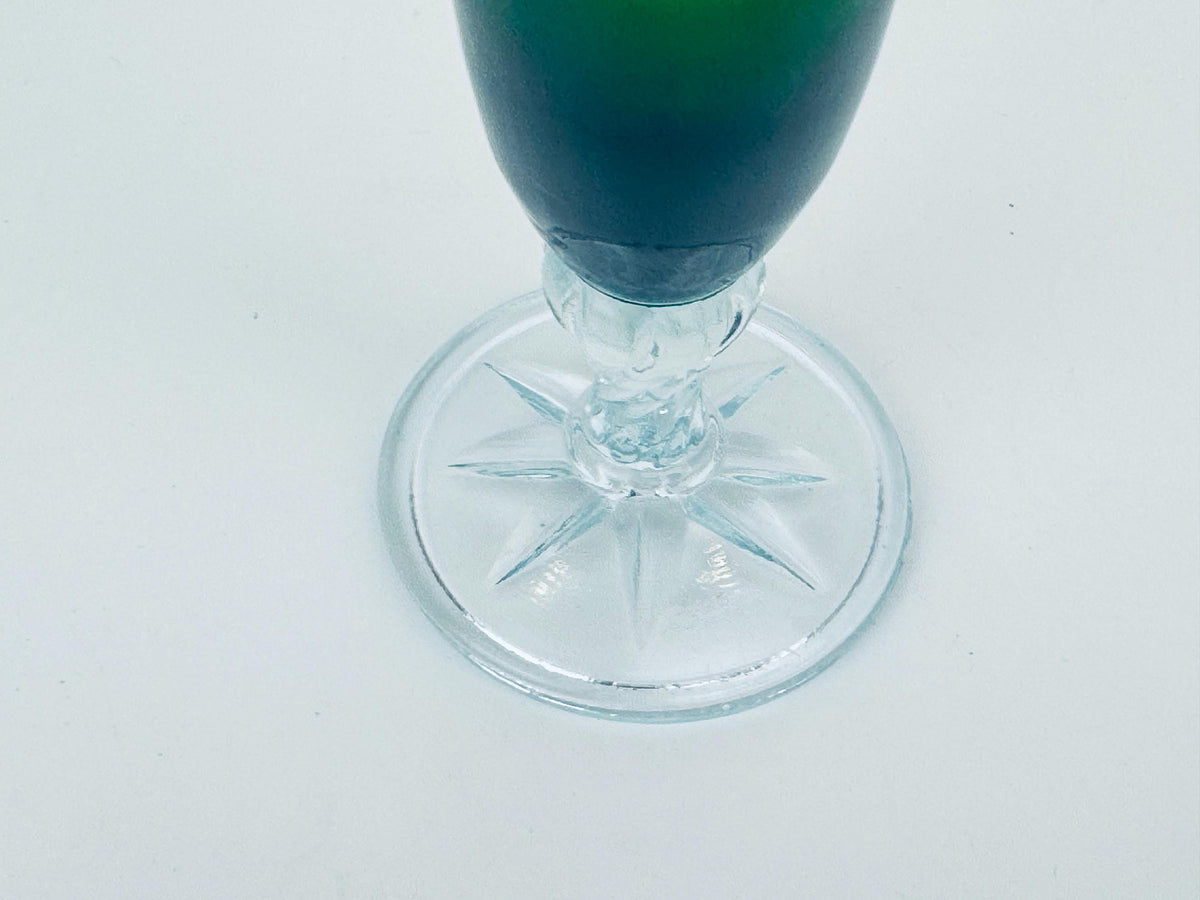 Clear glass with green liquid on a white background