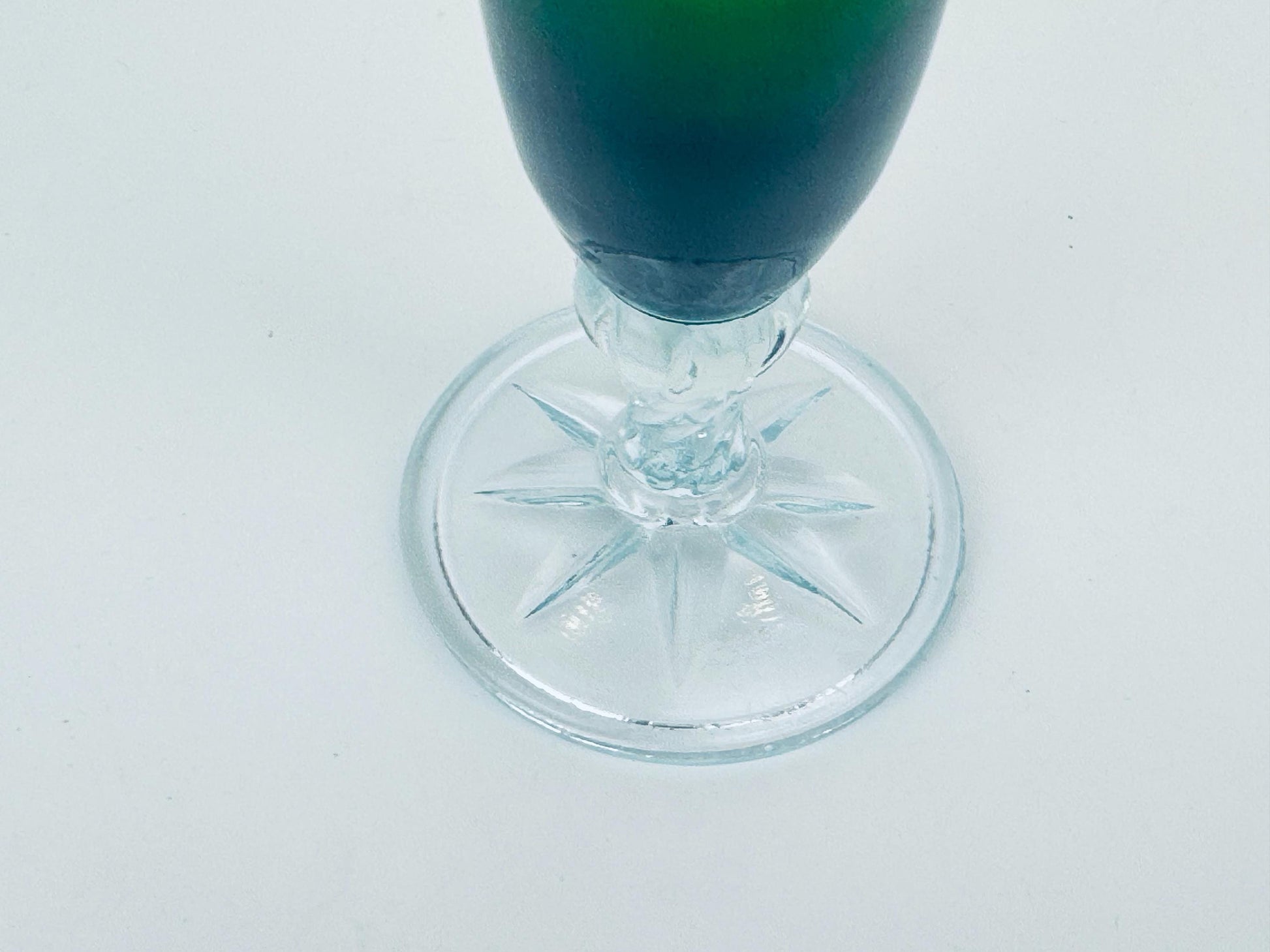Clear glass with green liquid on a white background