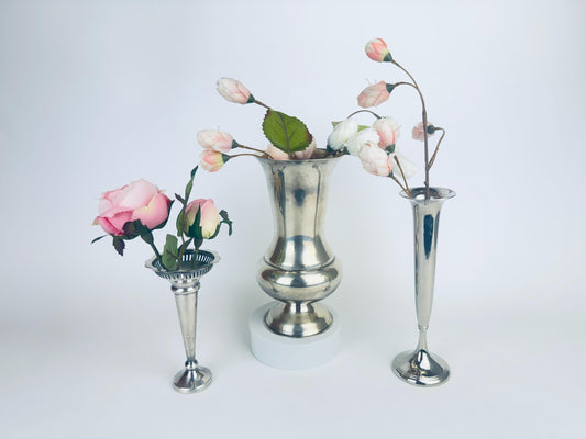 Three silver vases with floral arrangements on a white background