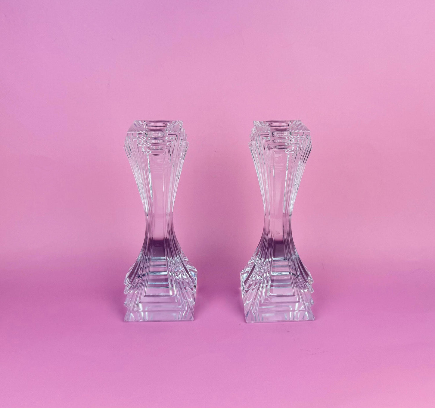 Two crystal candle holders on a pink background