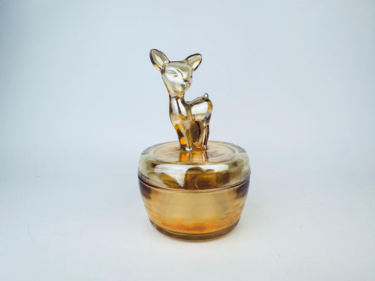 Amber glass jar with a deer figurine on a light gray background