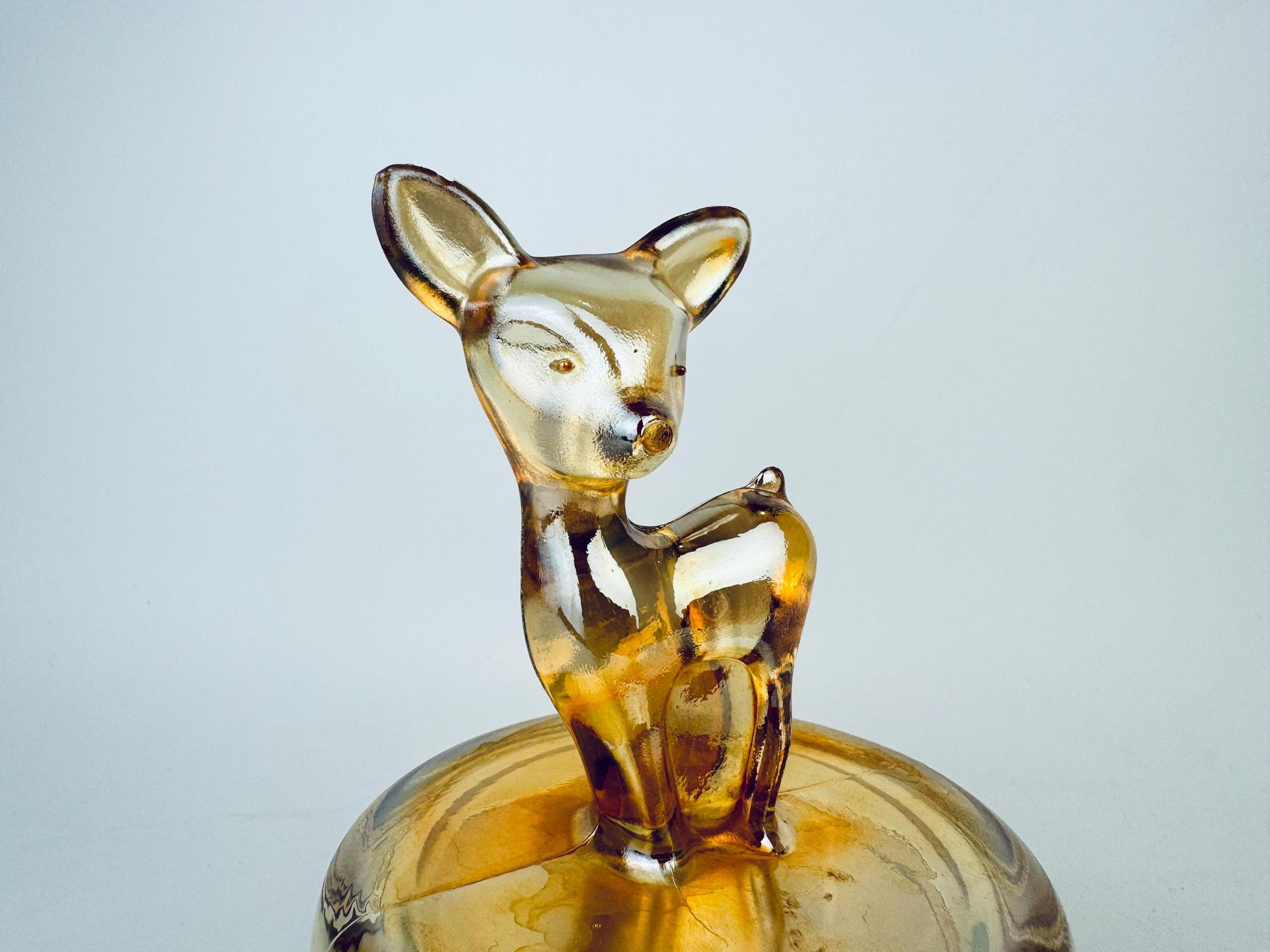 Glass deer figurine on a clear base against a light gray background