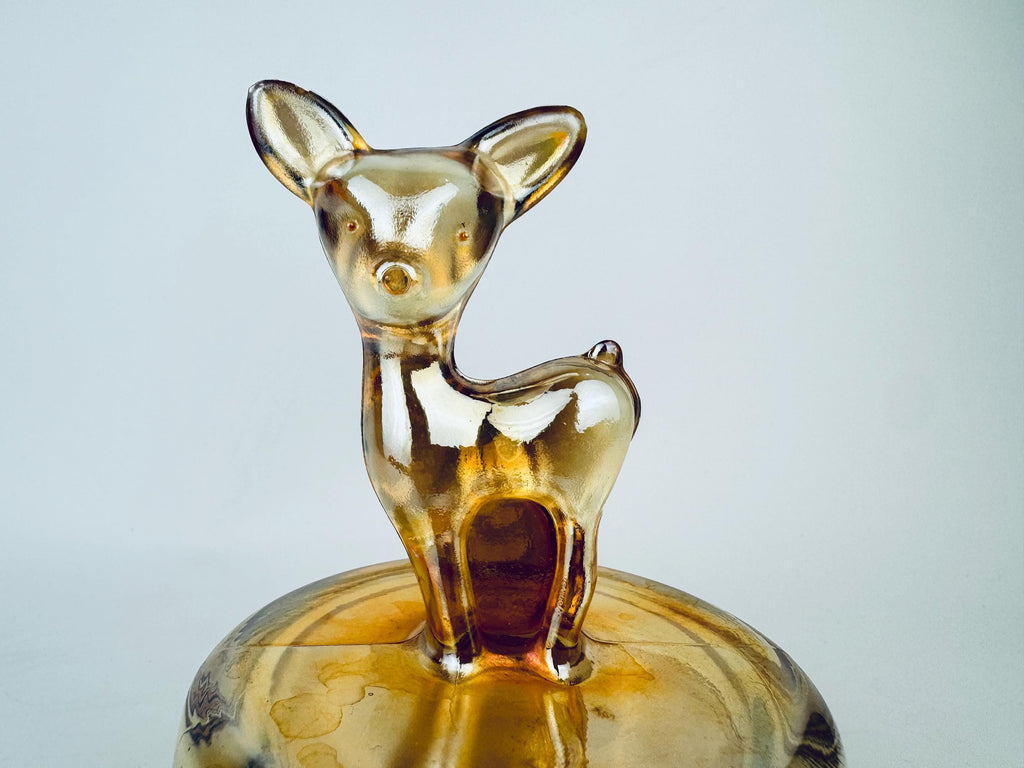 Glass deer figurine on a matching base against a light gray background