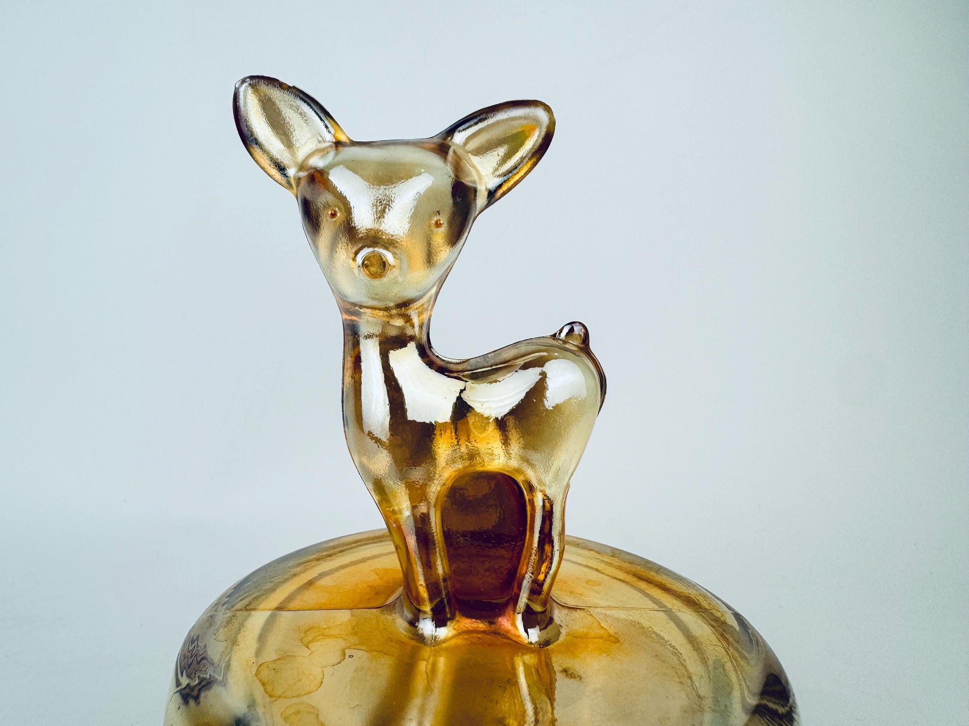 Glass deer figurine on a matching base against a light gray background