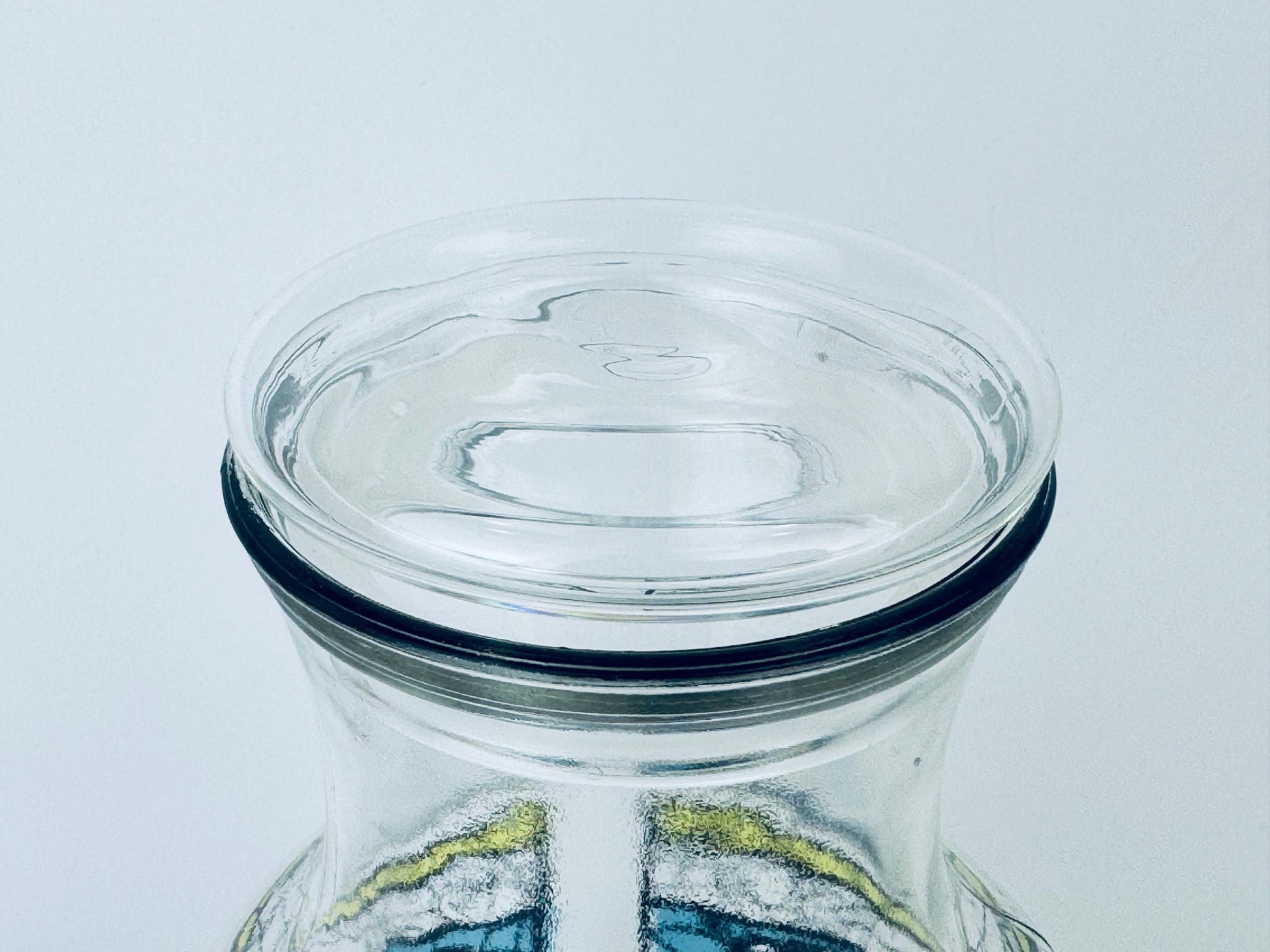 Clear glass jar with a lid on a light gray background