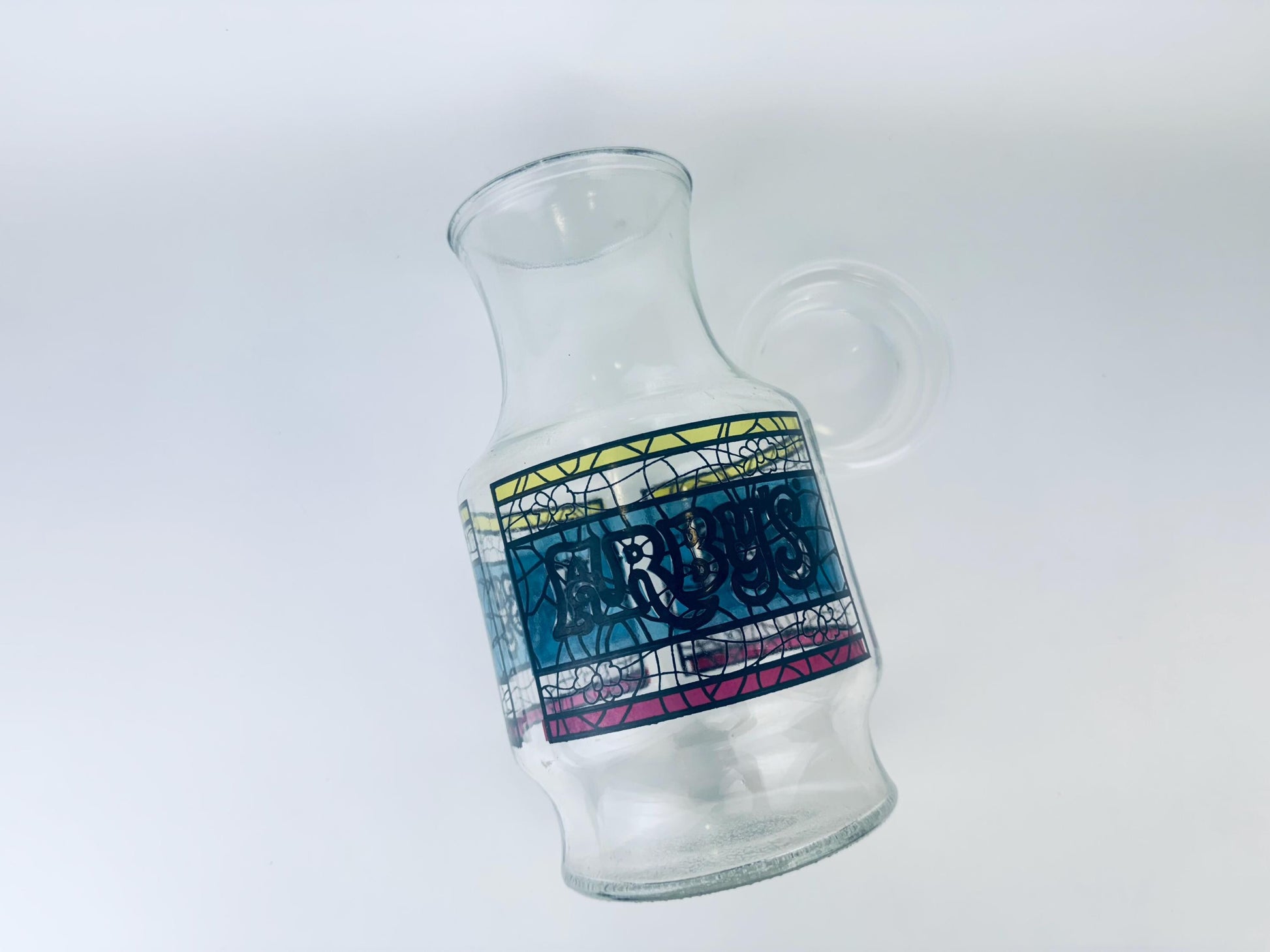 Clear glass carafe with a colorful label on a white background
