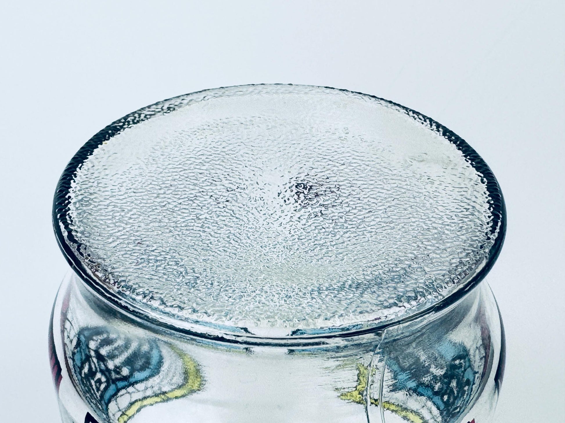 Clear glass jar with decorative bottom on a white background