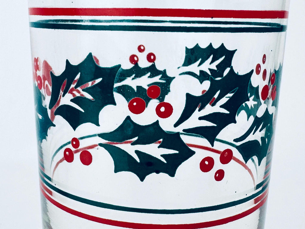 Glass with holly design and red and green accents on a white background