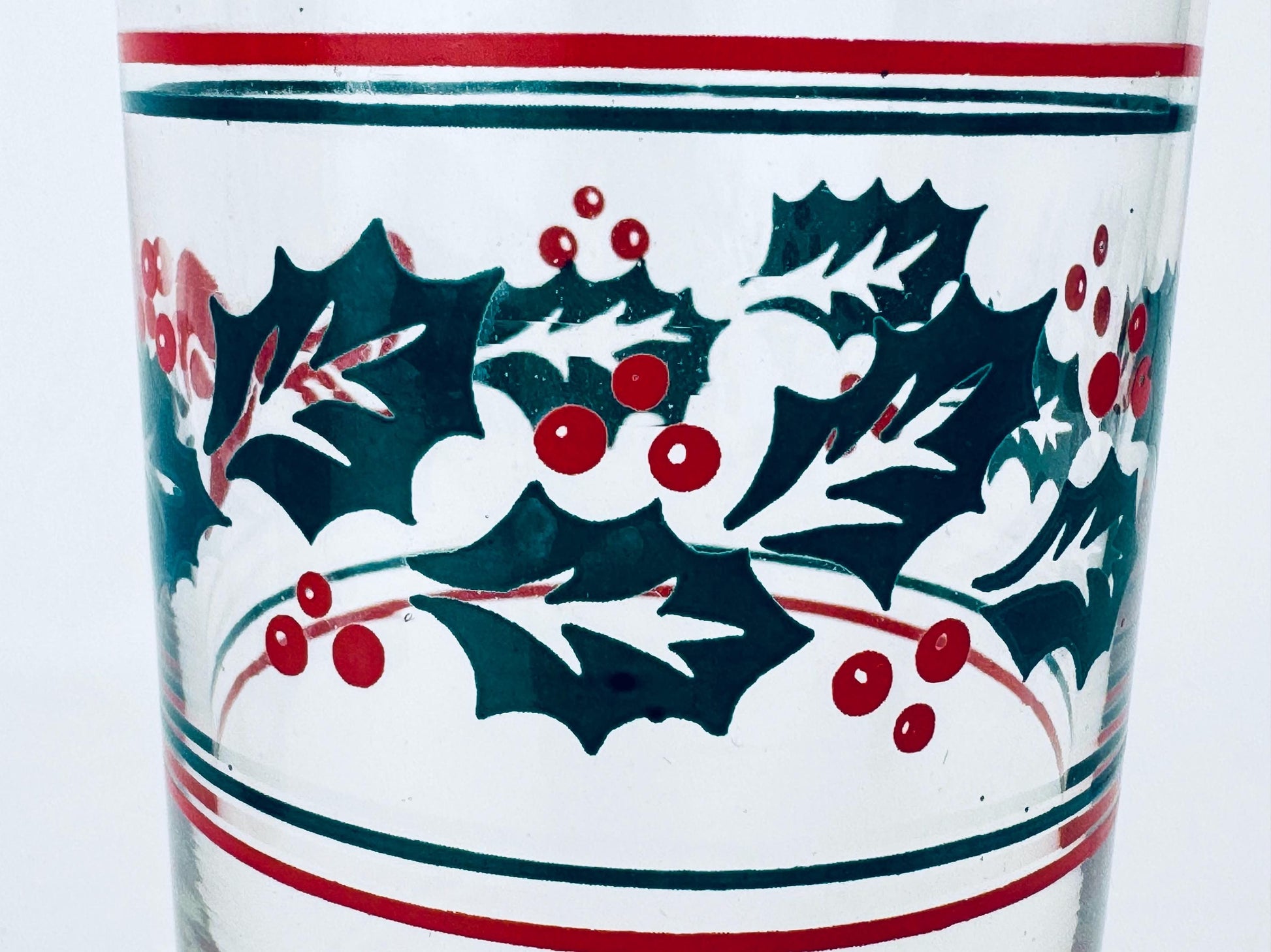 Glass with holly design and red and green accents on a white background