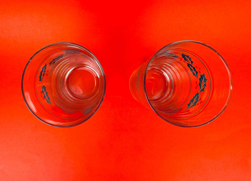 Two clear glass tumblers with black leaf patterns on a red background