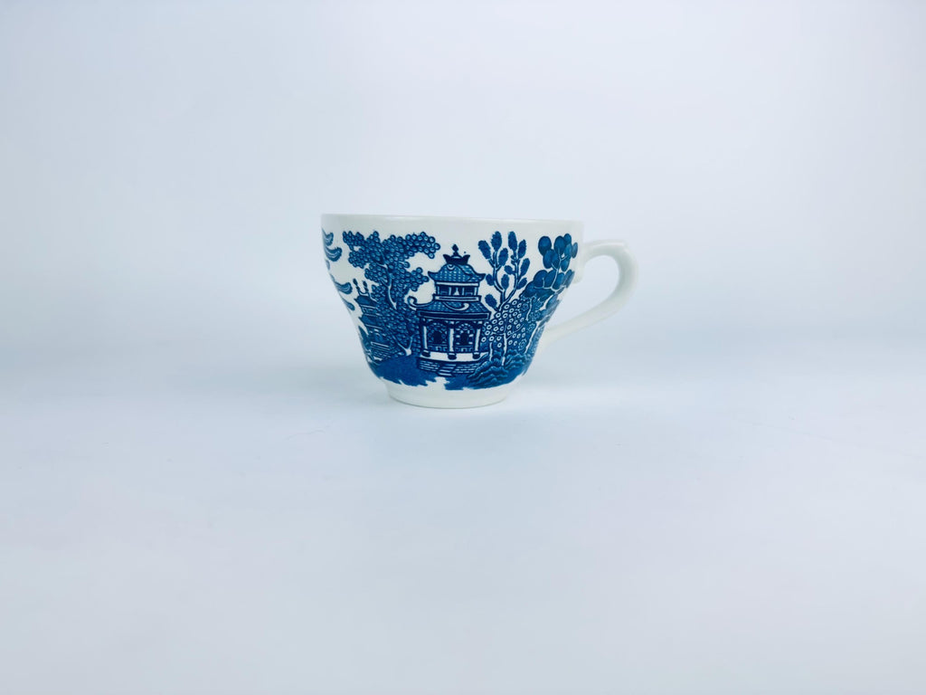 White teacup with blue floral and pagoda design on a white background
