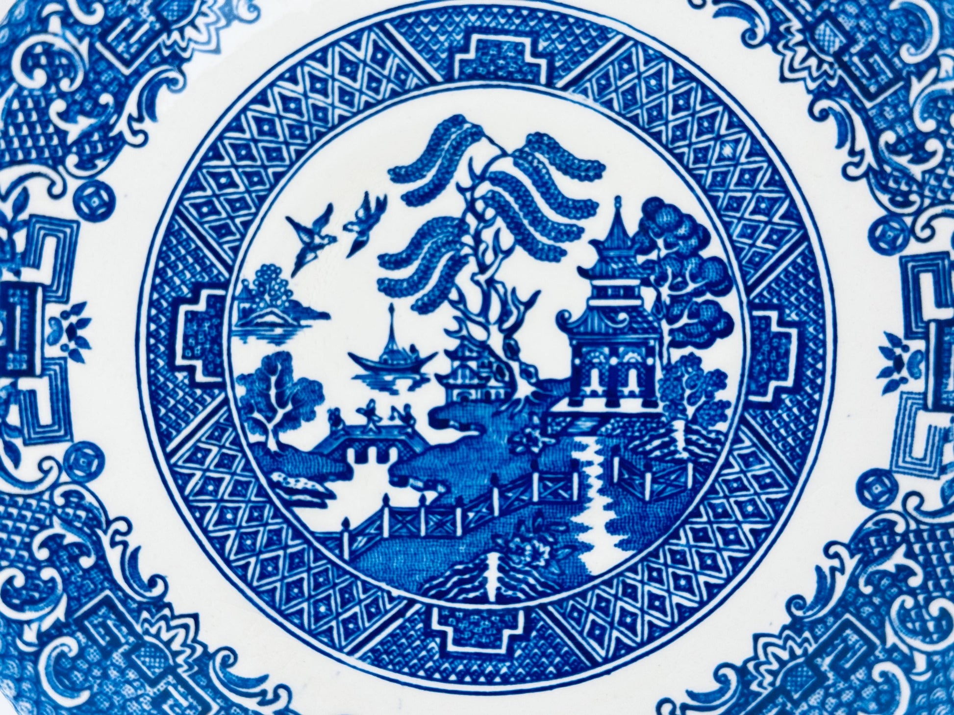 Blue and white ceramic plate with intricate design of landscapes and buildings.