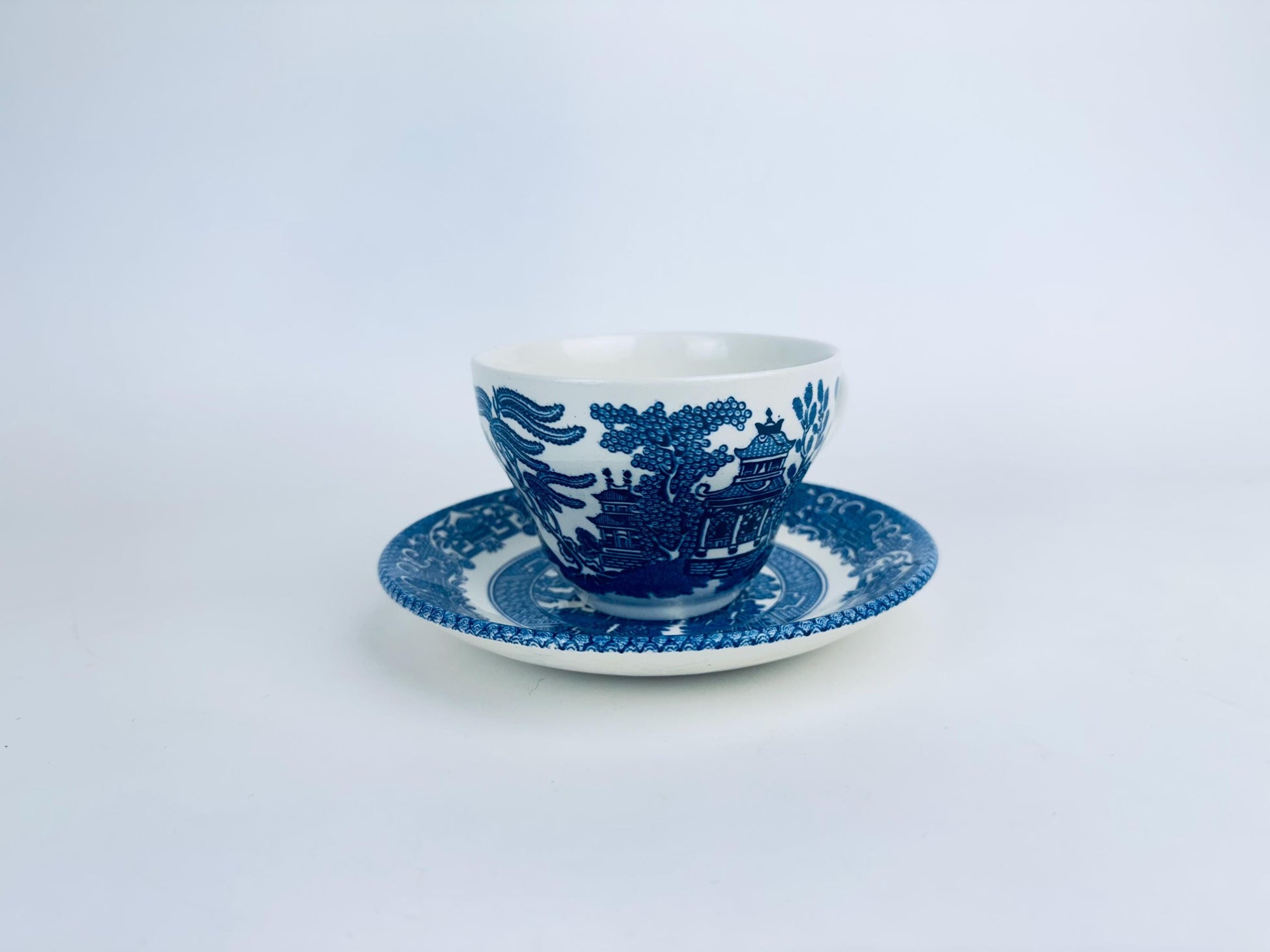 Blue and white ceramic cup and saucer on a light gray background
