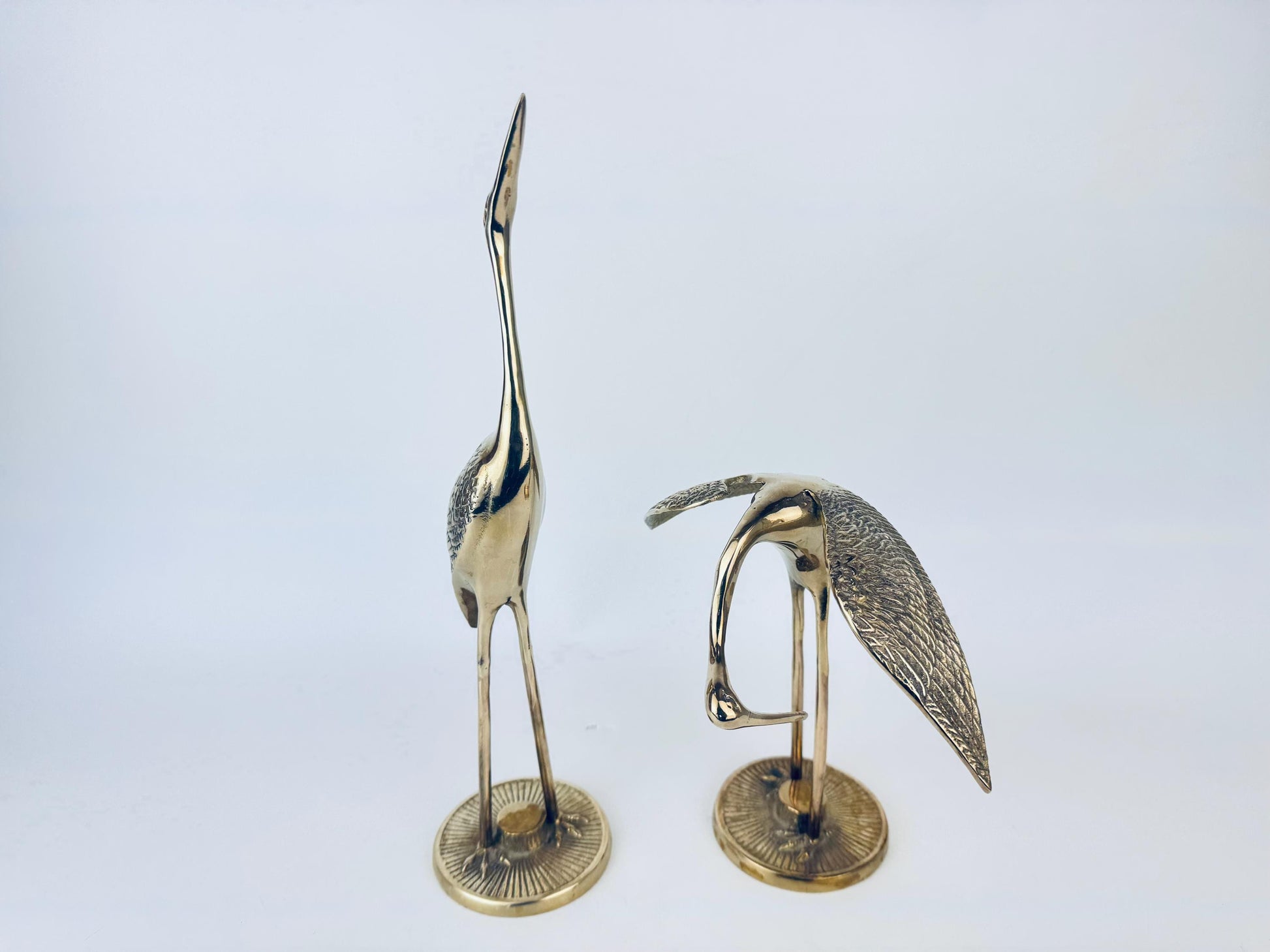 Two brass bird sculptures on a white background