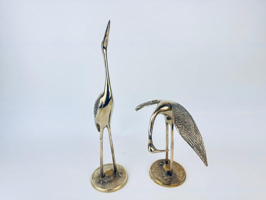 Two brass bird sculptures on a white background