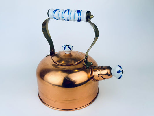 Copper kettle with blue and white handle on a white background