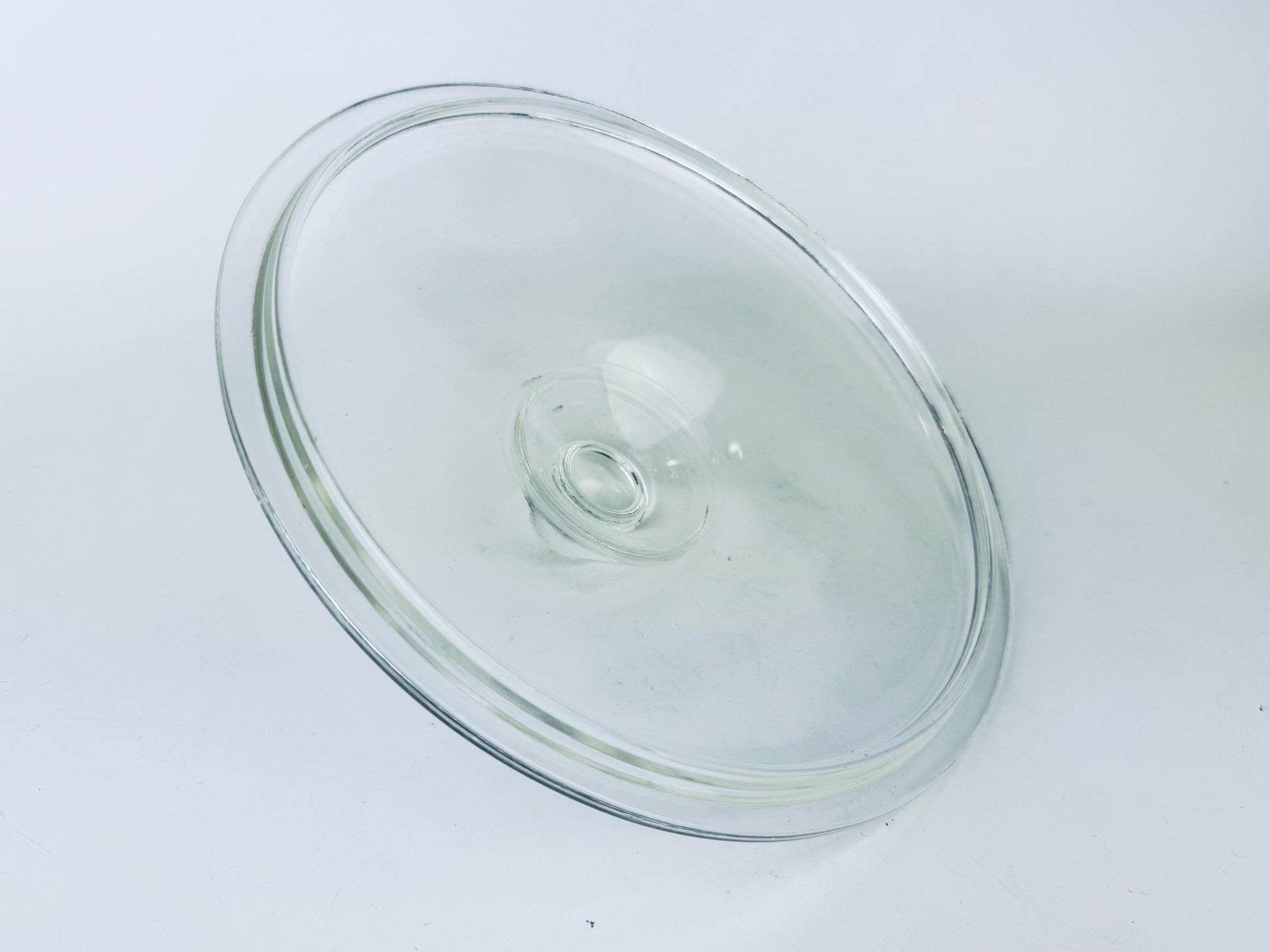 Clear glass pie dish lid on a white background