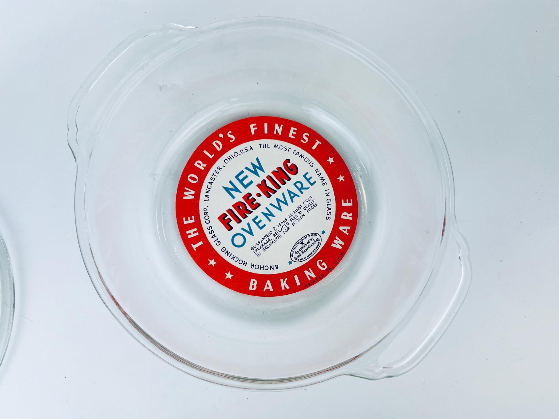 Red label on a clear plastic container with 'New Fire-King Ovenware' text.
