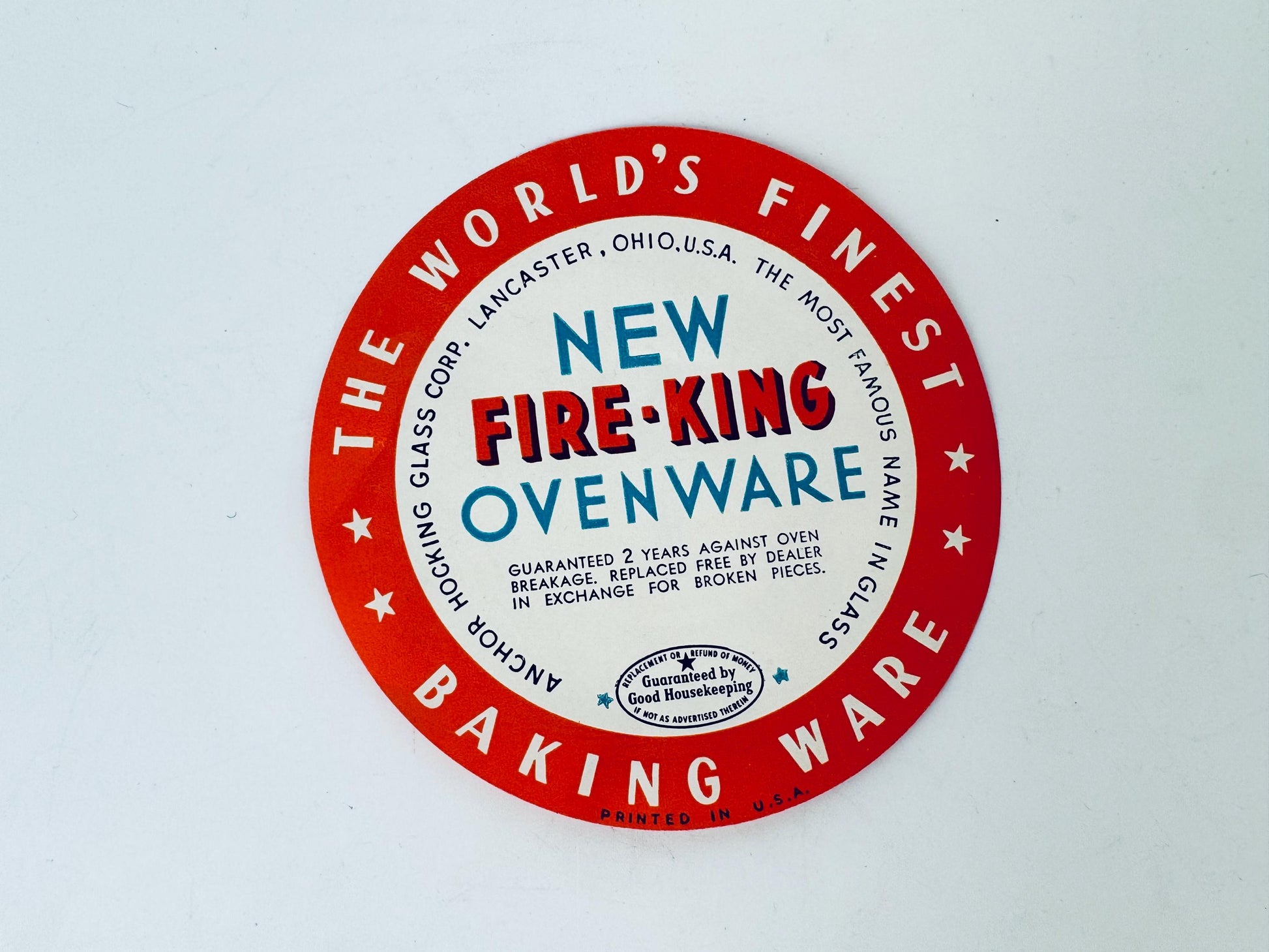 Round red label for New Fire-King Ovenware on a white background