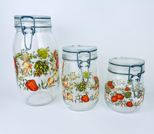 Three glass jars with floral designs on a white background