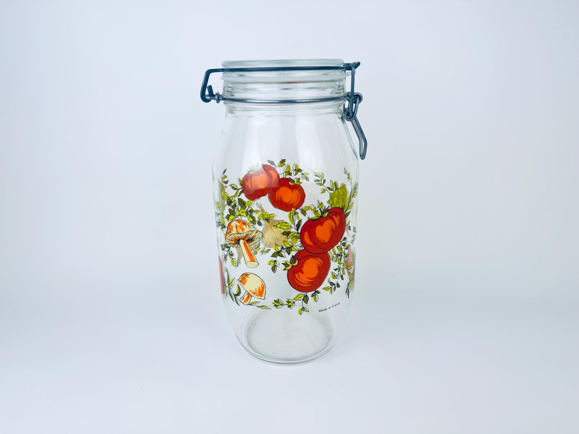 Glass jar with floral and vegetable design on a white background