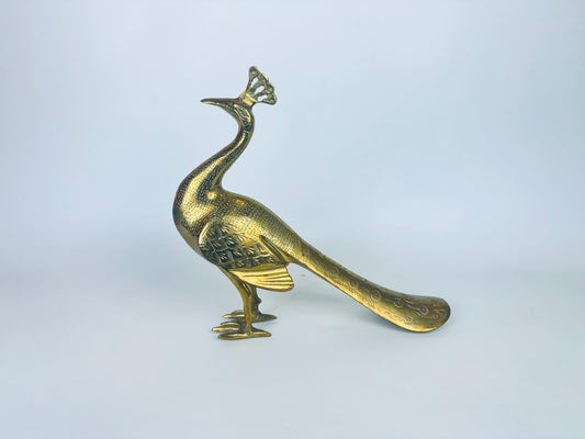 Gold peacock figurine on a light gray background