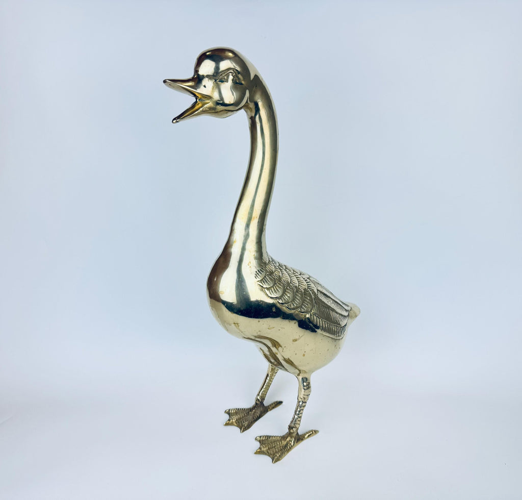 Brass goose figurine on a light gray background