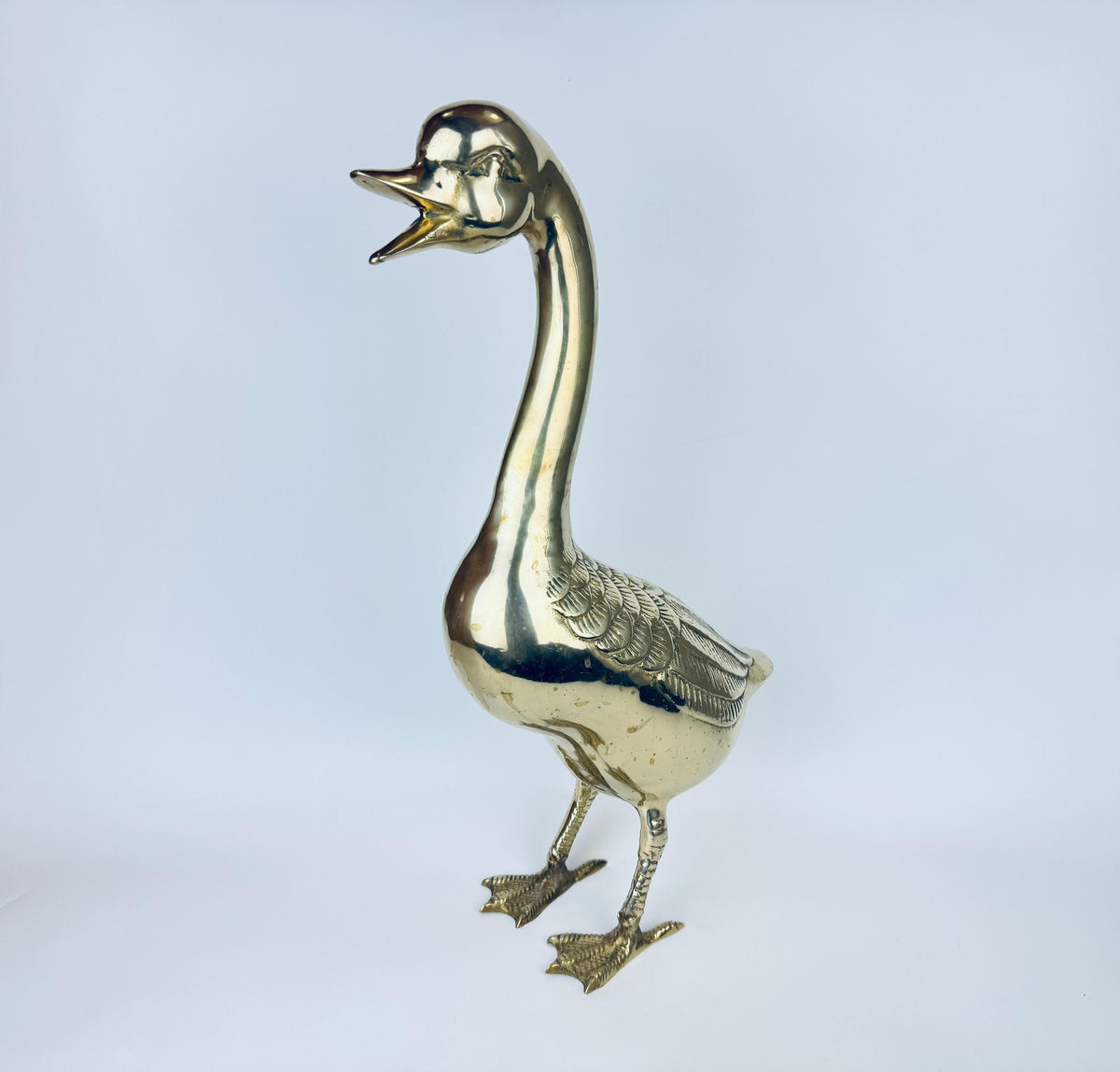Brass goose figurine on a light gray background