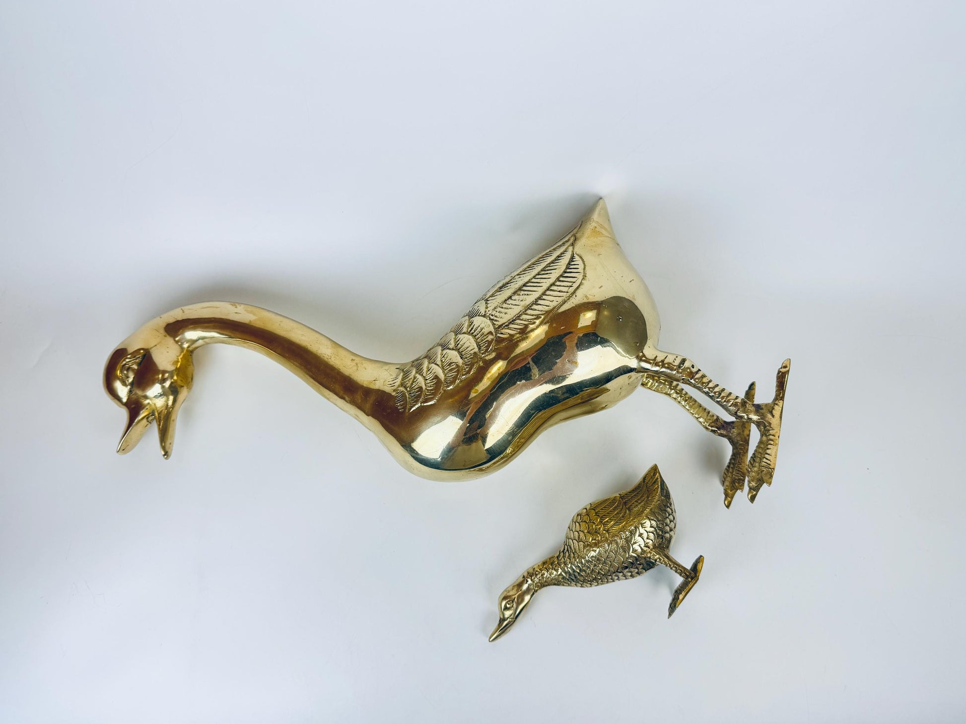 Gold decorative item resembling two ducks on a white background