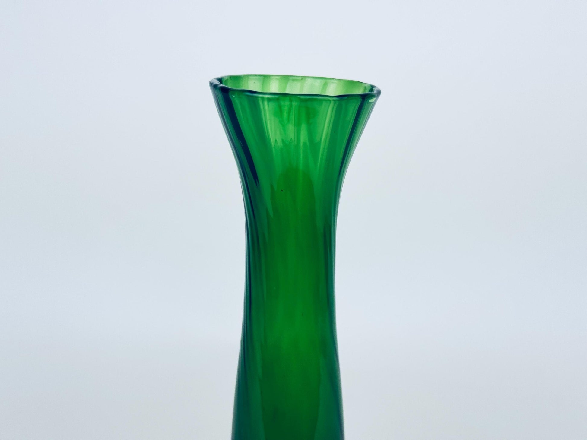 Green glass vase on a light gray background