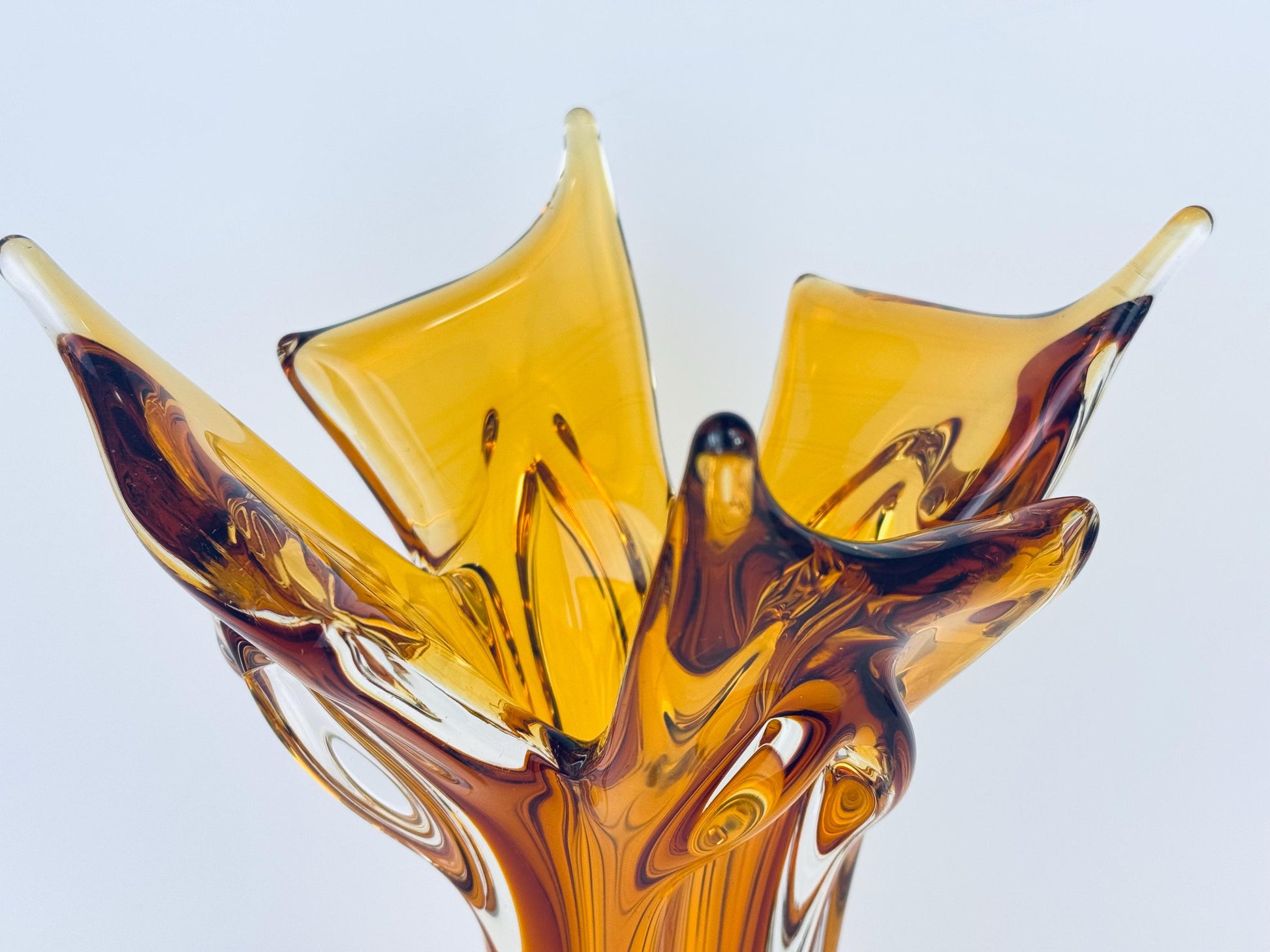 Artistic glass sculpture with amber and brown colors on a light gray background