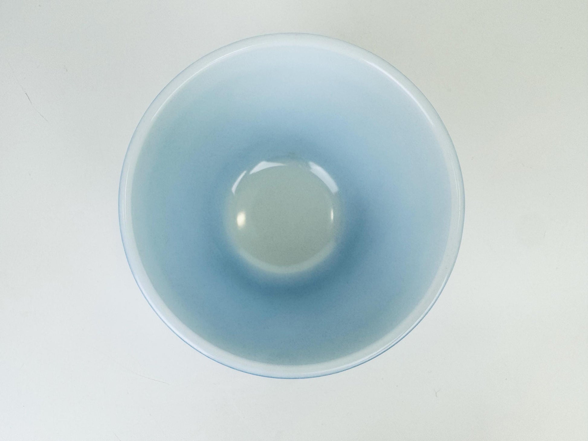 Glass bowl with a gradient blue to white color on a light gray background