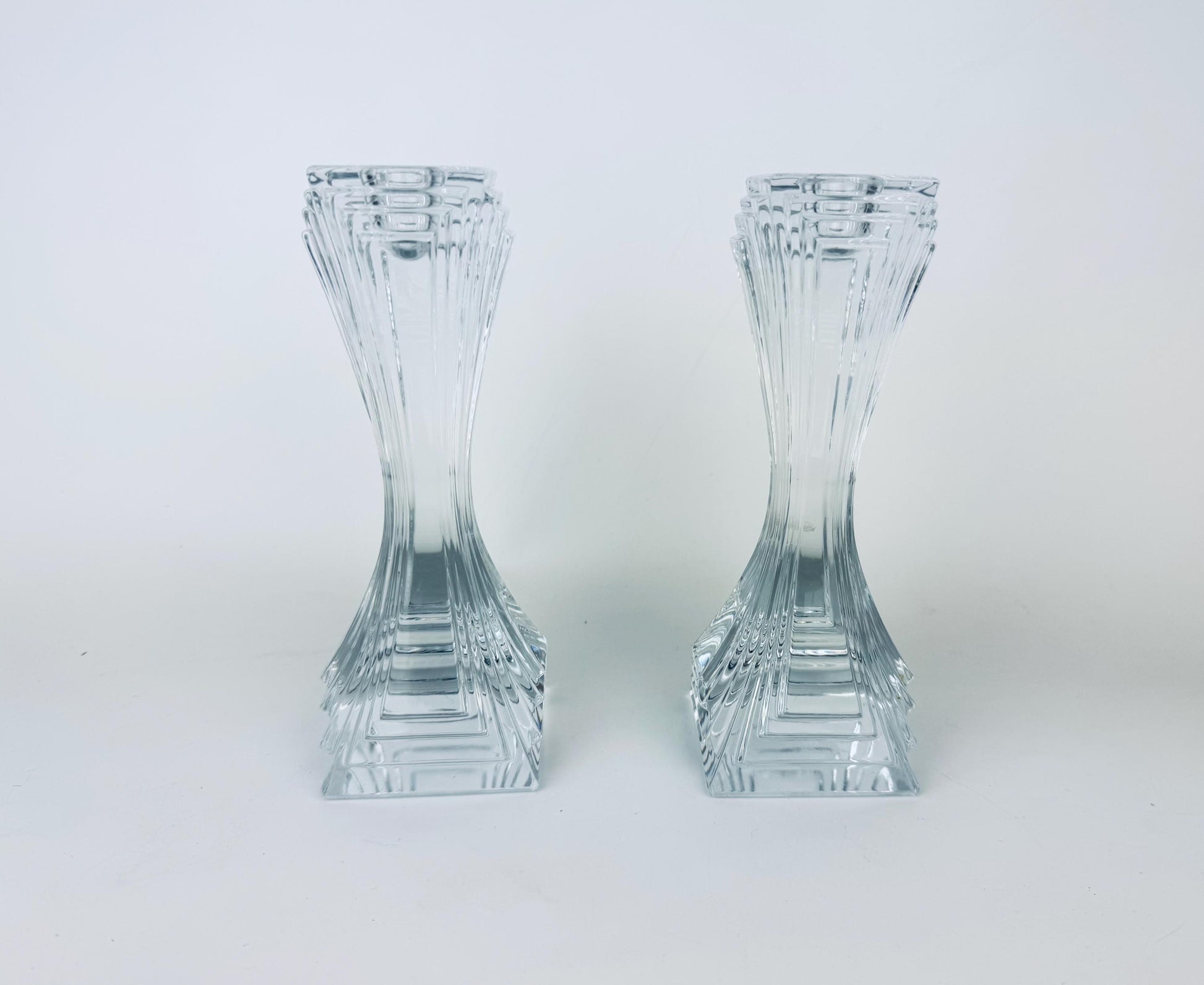Two clear glass candle holders on a white background