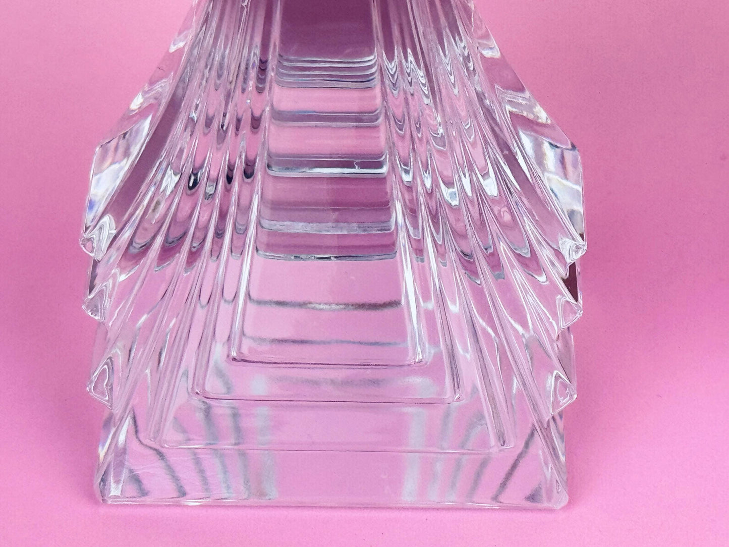 Clear glass pyramid-shaped object on a pink background