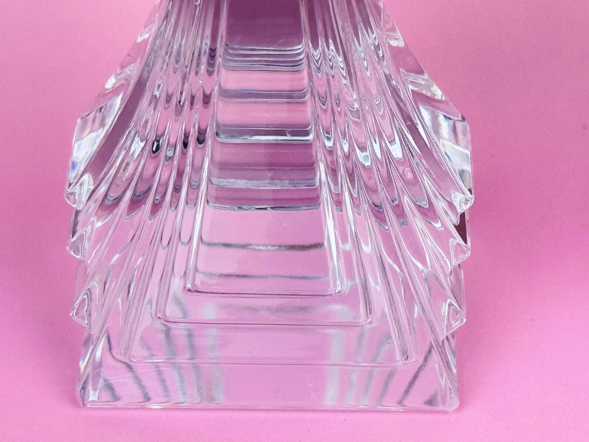 Clear glass pyramid-shaped object on a pink background