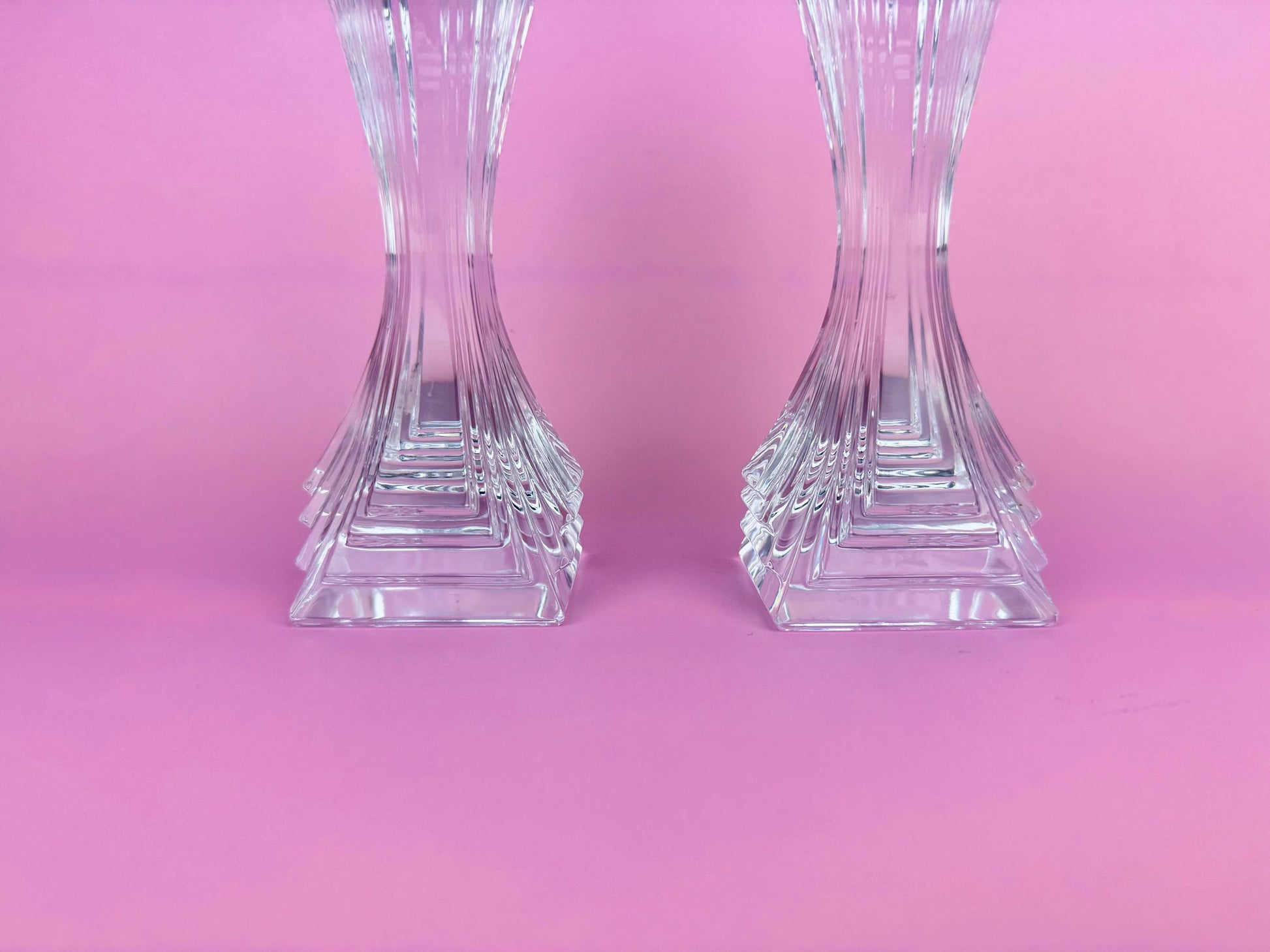 Two crystal candle holders on a pink background