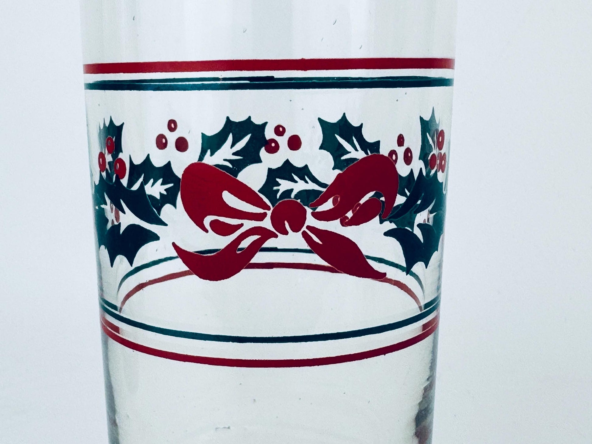 Clear glass with red bow and holly design on a white background