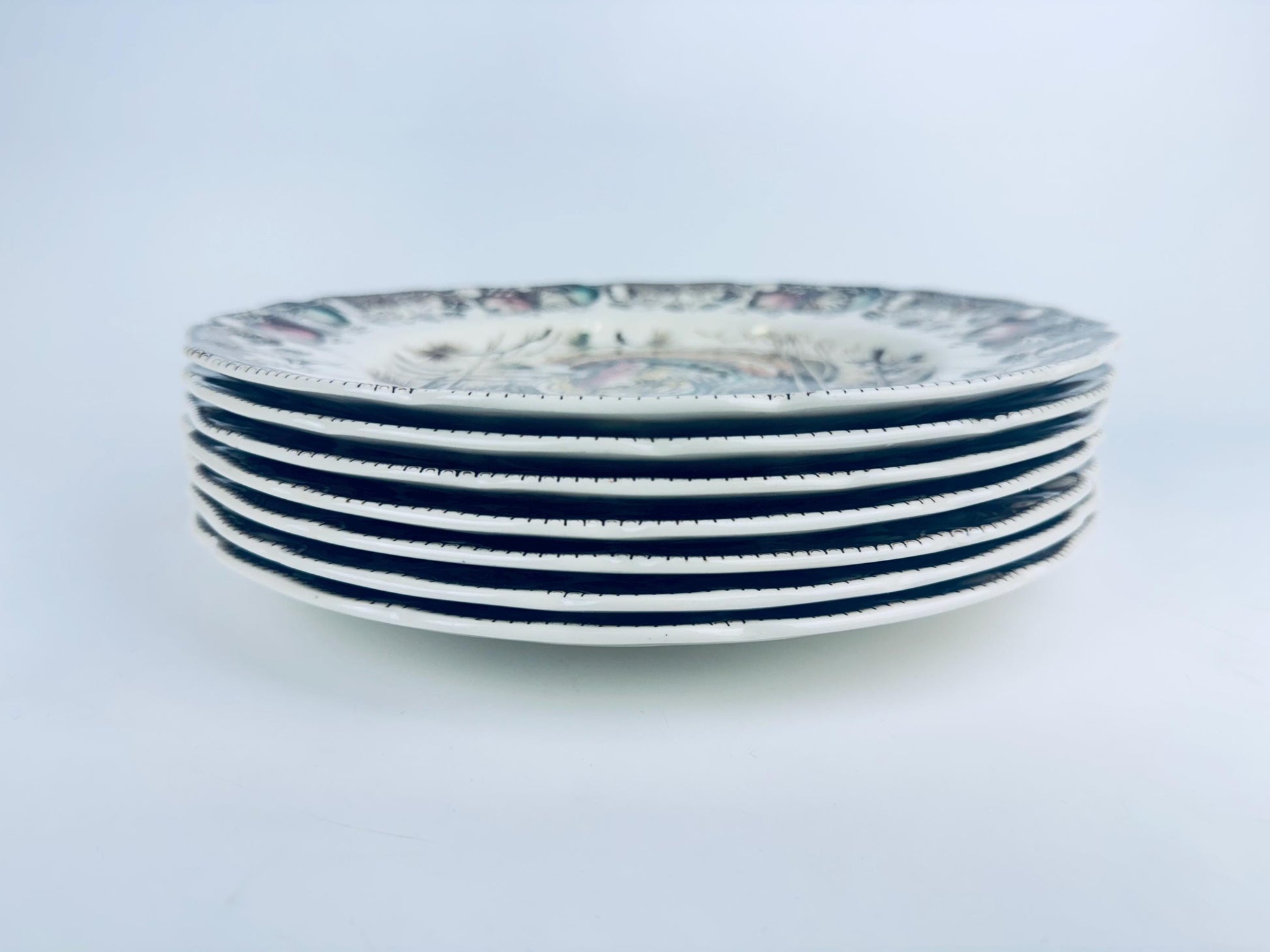 Stack of ceramic plates with brown and beige design on a light gray background
