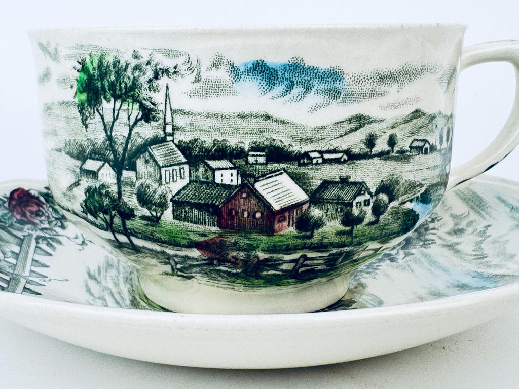 Teacup with scenic village design on a white background