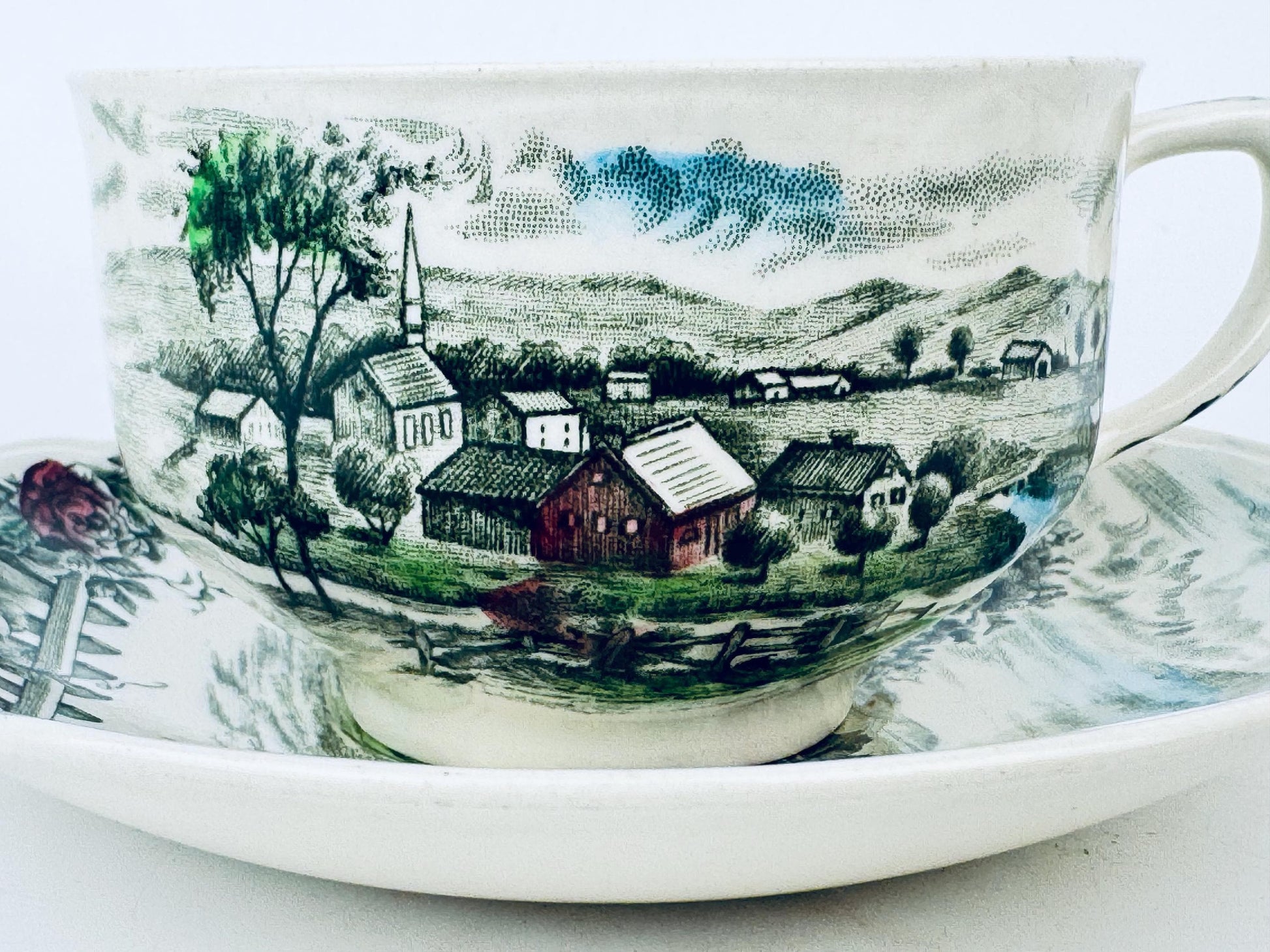 Teacup with scenic village design on a white background
