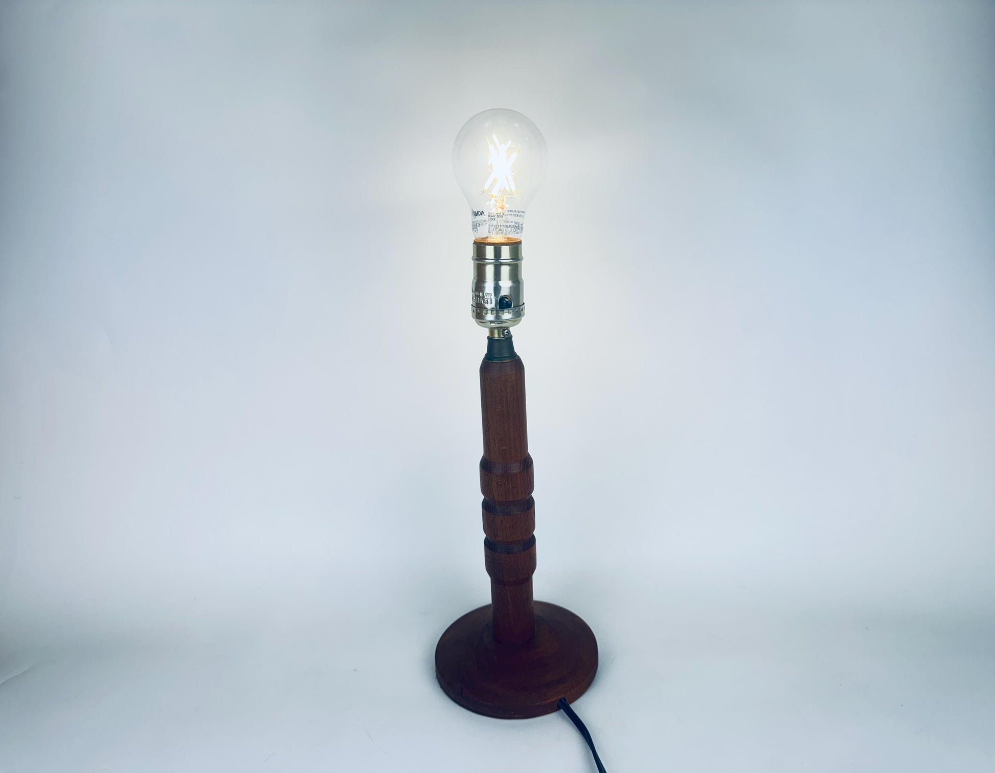 Wooden lamp with a lit bulb on a white background