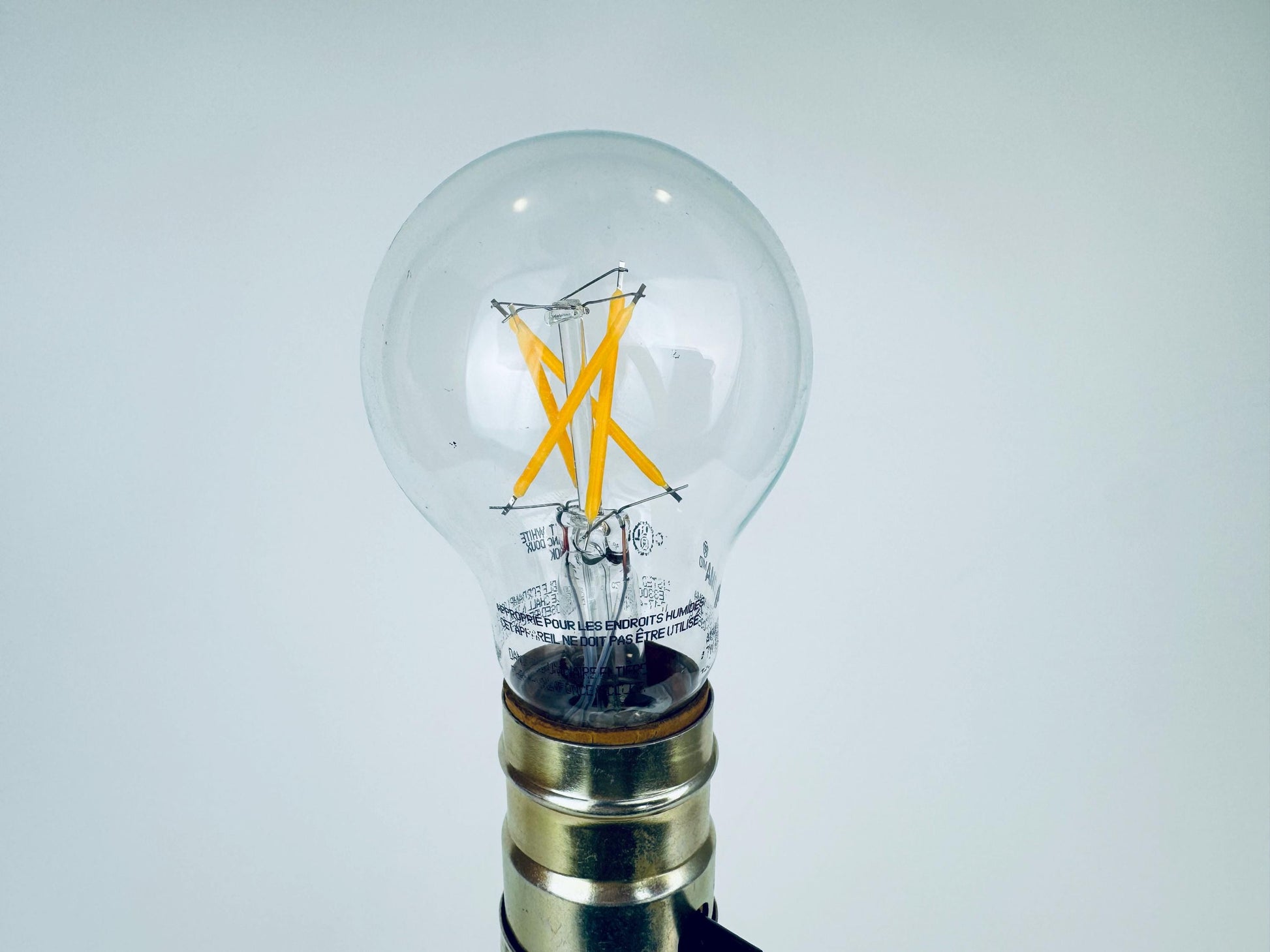 Clear light bulb with visible filament on a white background