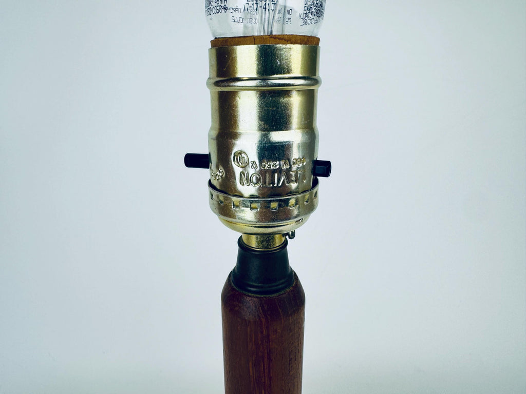 Vintage-style lamp with brass fitting and wooden base on a white background