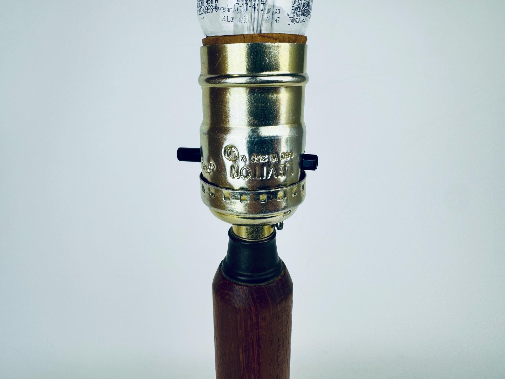 Vintage-style lamp with brass fitting and wooden base on a white background