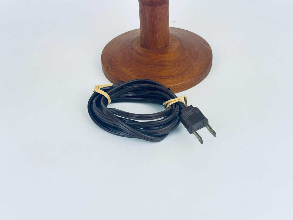 Wooden lamp base with black electrical cord and plug on a white background