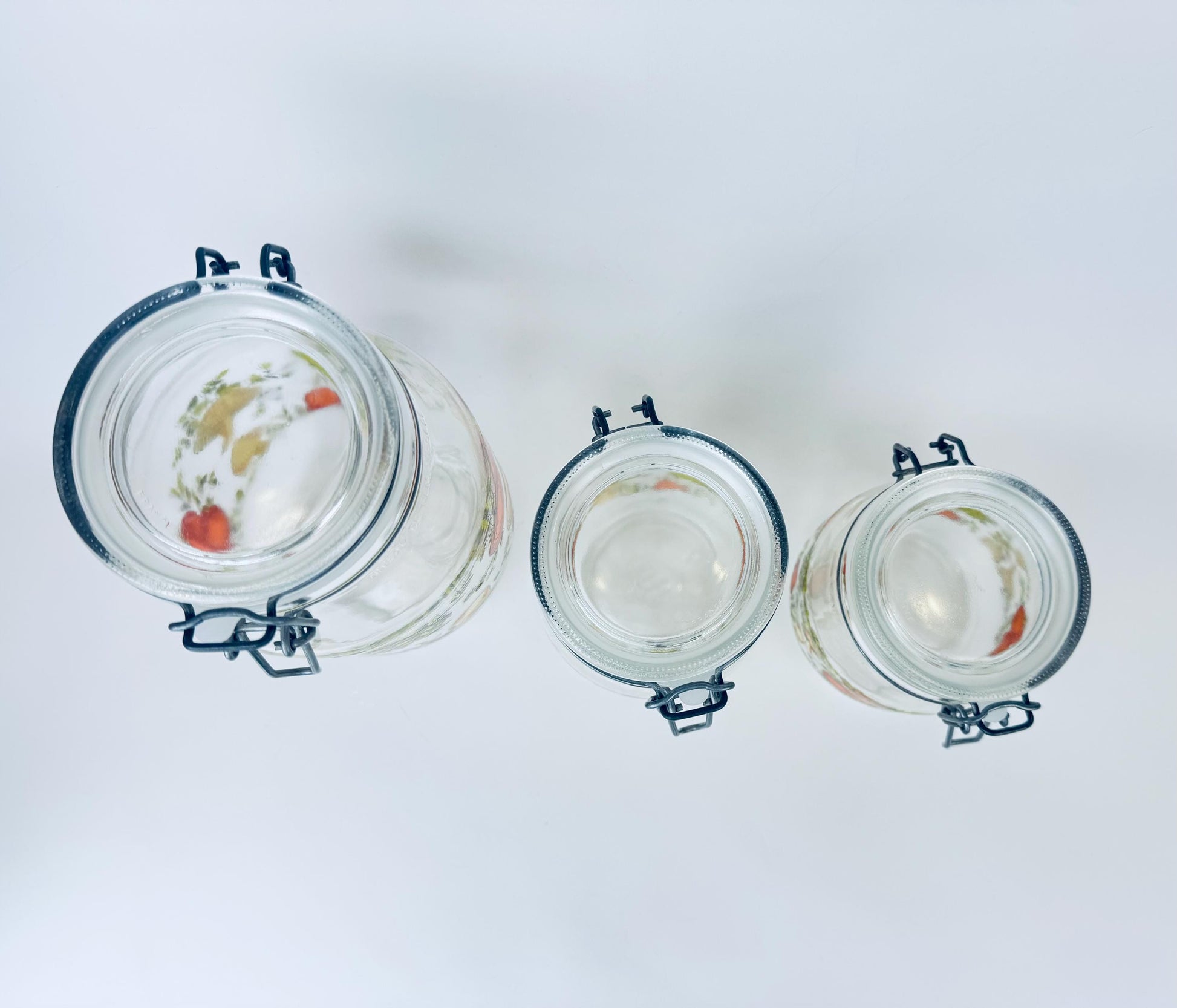 Three glass jars with metal clamps on a white background