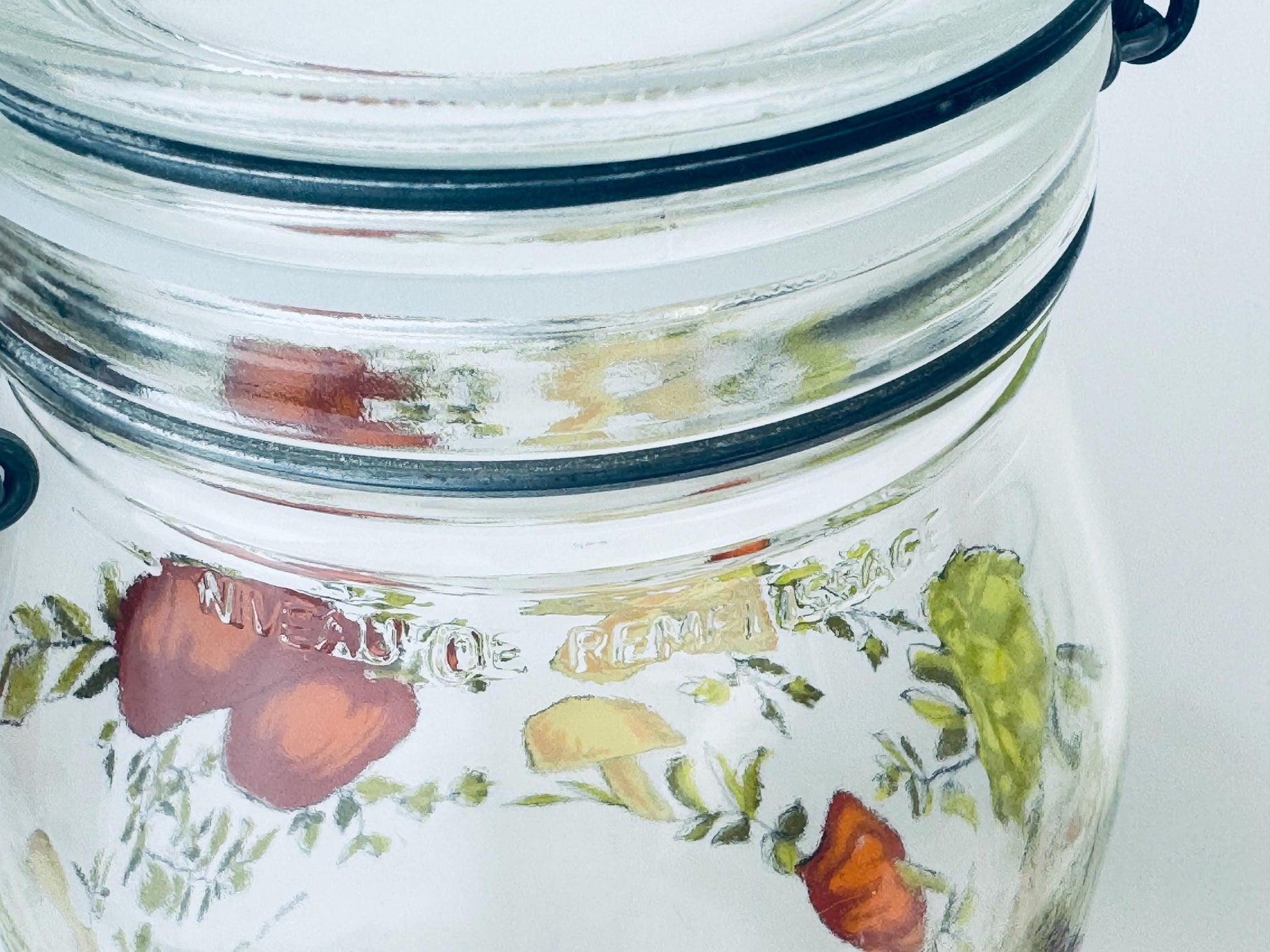 Glass jar with floral design and lid on a white background