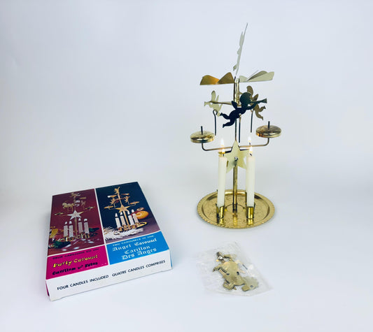 Decorative candle holder with angel design next to packaging on a white background