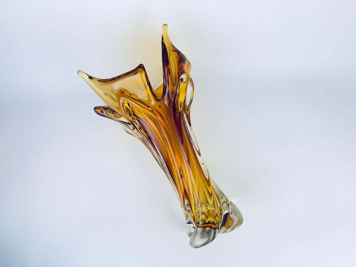 Glass sculpture vase in amber and clear colors on a white background